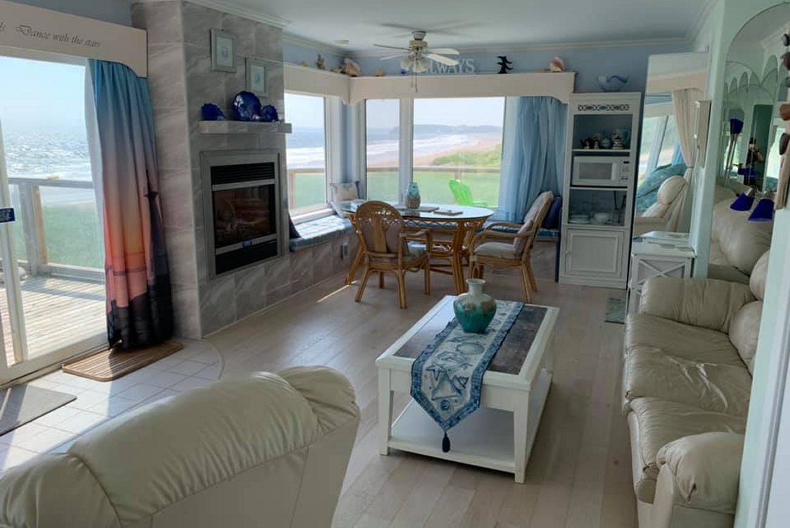 Sea Spray suite spacious living room with huge windows on 3 sides overlooking the beach
