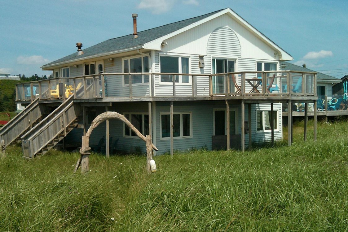 Exterior view of Moonlight Beach Suites, with windows and extensive decks, nestled in beach grass